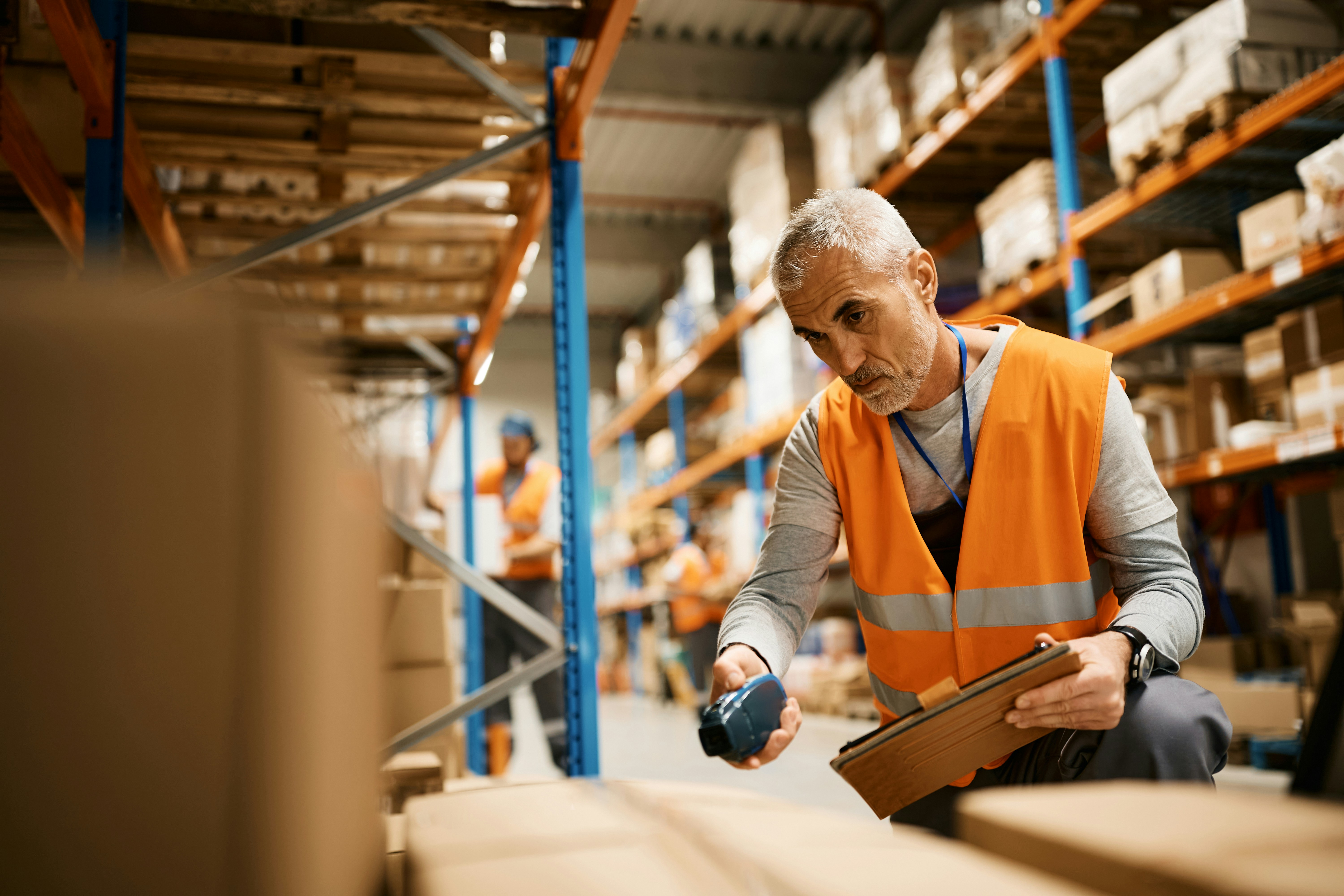A man in a warehouse scanning inventory, holding a tablet